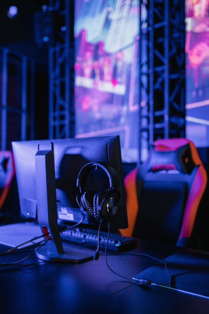 A modern gaming setup featuring a computer monitor and headset in a neon-lit environment.